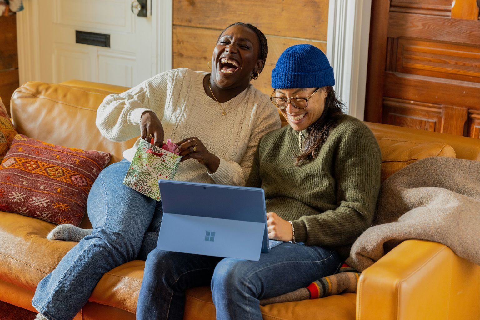 Deux amies 50+ qui rient ensemble sur un canapé